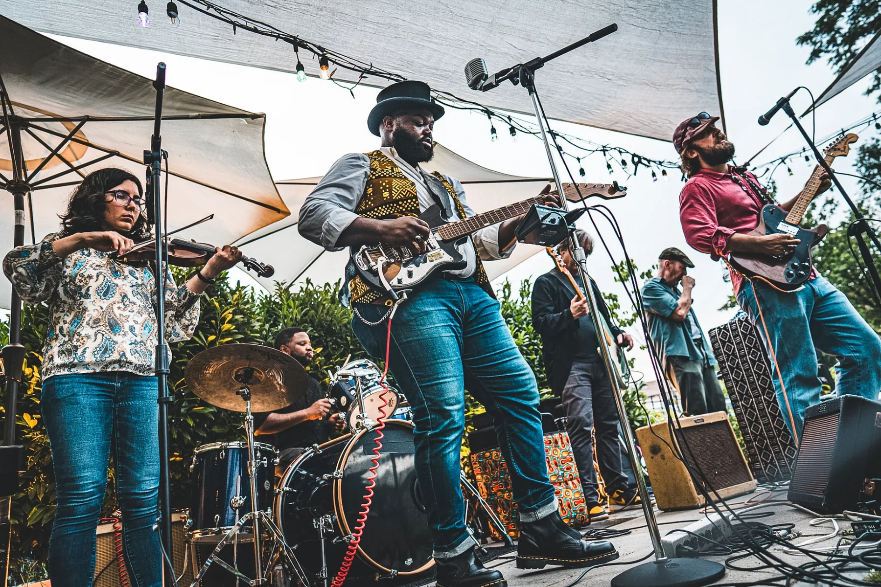 Cuppa T Jones playing electric guitar with his band on an outdoor stage.