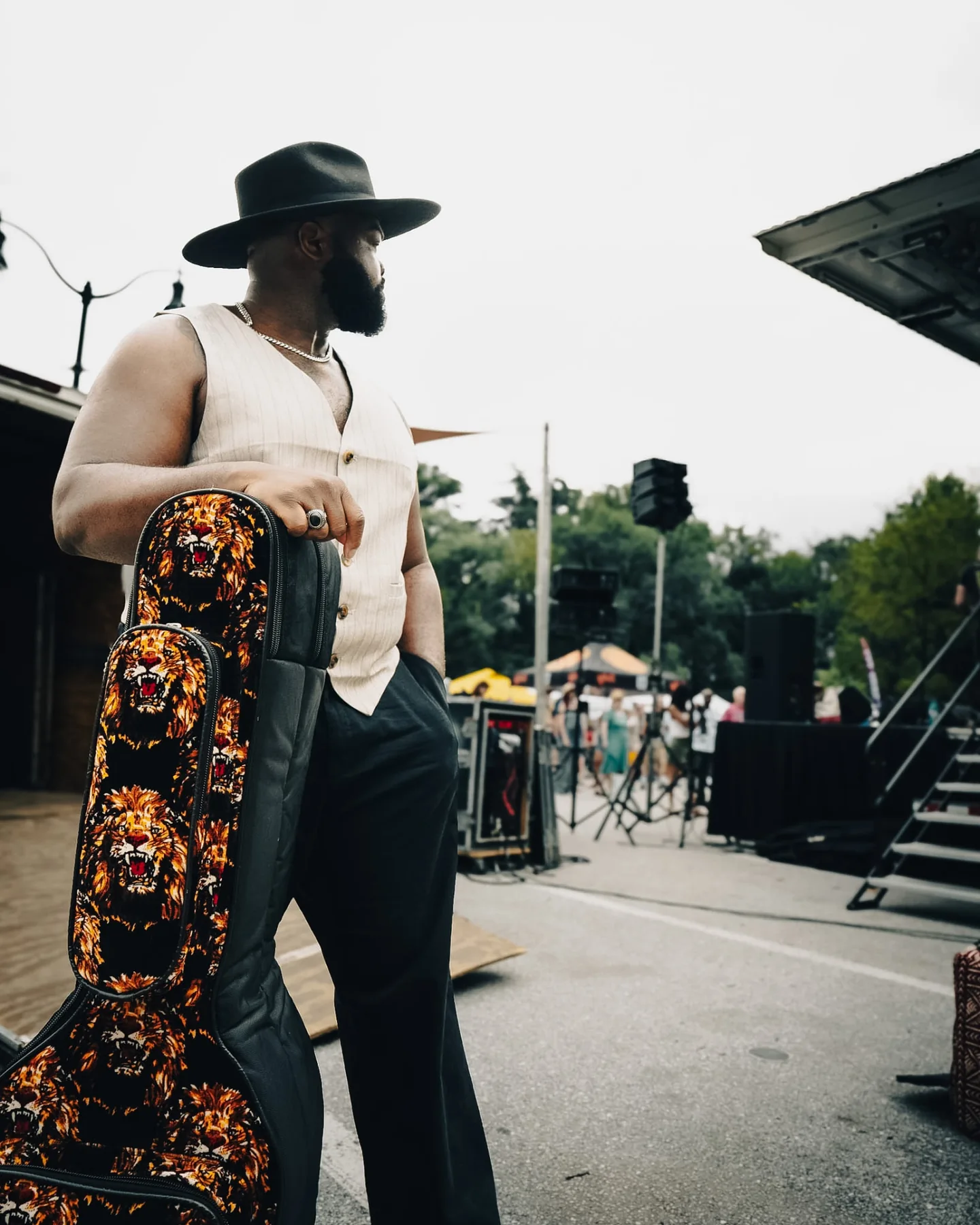 Cuppa T Jones holding his guitar case backstage before a show.